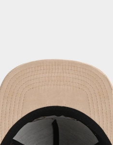 Close-up of curved beige cap brim featuring five rows of precise parallel stitching