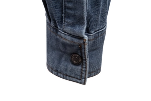 Gros plan du poignet d'une chemise en jean bleu délavé avec bouton en métal et coutures