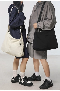 Macro detail of large nylon messenger bags in black and beige on models showing scale