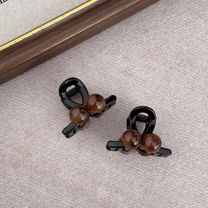 Macro detail of high-shine amber cherry claw clips with polished brown beads