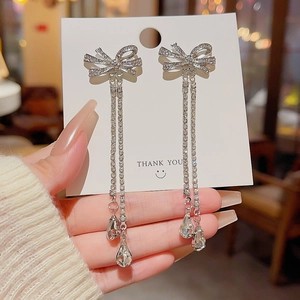 Detail of silver bow earrings with sparkling crystal tassels and teardrop pendants
