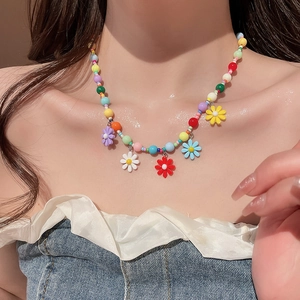 Close-up of colorful beaded daisy necklace featuring five vibrant flower charms on a model