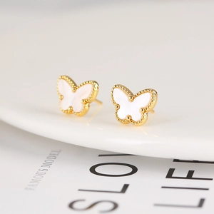Macro shot of gold-plated butterfly stud earrings with white resin inlay details