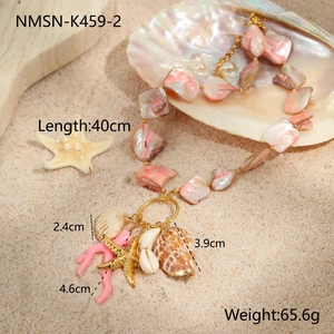 Detail of pink shell necklace with starfish and coral pendants on a sandy beach