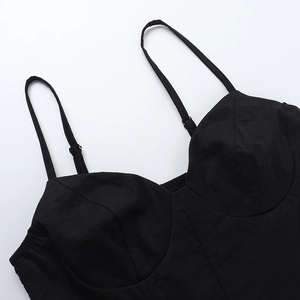 Detail of black corset top featuring slim straps and structured pleated cup design