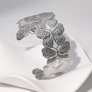 Close-up of a silver butterfly open cuff bracelet with detailed texture on a white wave stand