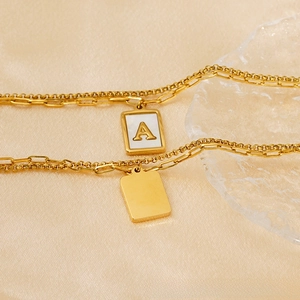 Vue rapprochée du bracelet doré multicouche avec pendentif lettre A en nacre blanche