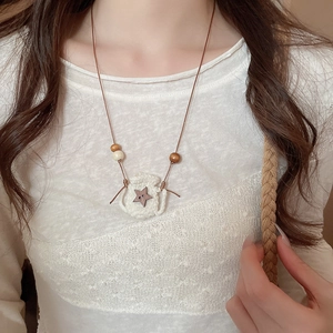 Detail of hand-crocheted white pouch pendant necklace with wooden star button and beads