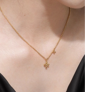 Close-up of minimalist 18K gold-plated titanium steel necklace with beaded cross charms