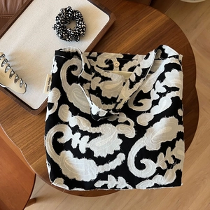 Detail view of the black and white paisley embroidery with fringe texture and magnetic closure