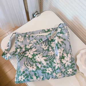 Dettaglio della borsa tote floreale in tela con motivi blu ed etichetta del marchio