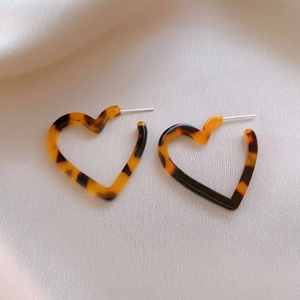 Detailed view of heart-shaped leopard print resin earrings with silver needles