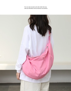 Vista posteriore di una modella con borsa a tracolla a mezzaluna in nylon rosa in studio