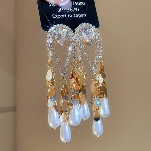 Detail of luxury teardrop pearl drop earrings with sparkling heart-shaped crystals