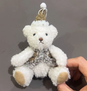 Detailed close-up of a plush white teddy bear ornament in a brown knitted hat and vest