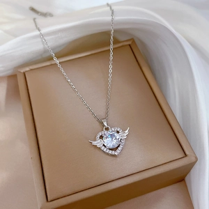 Macro shot of silver angel heart necklace with zircon on elegant white silk background