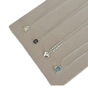 Elegant silver necklaces with heart pearl and gemstone pendants on grey velvet