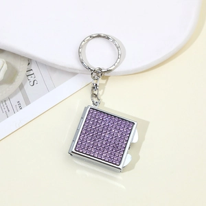 Macro shot of silver metal square keychain mirror with shiny purple rhinestones