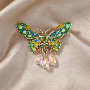 Close-up of colorful butterfly brooch with green rhinestones and waterdrop charms