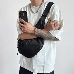 Close-up of black nylon crossbody chest bag and silver cuban chain jewelry on male model