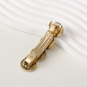 Close-up of golden vintage-style textured round metal hair clip on white background