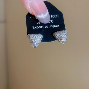 Détail des boucles d'oreilles triangulaires argentées serties de zircons brillants