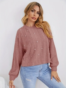 Détail d'un pull en maille côtelée mauve avec des perles blanches élégantes et poignets