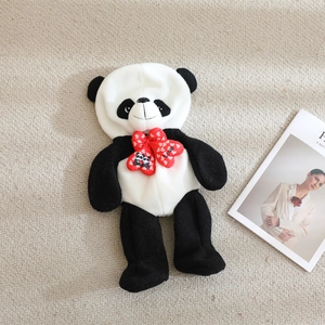 Cute black and white panda plush toy shell with a red love heart bow on soft carpet