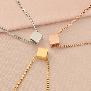 Three square cube pendant necklaces in gold, silver and rose gold on pink fabric