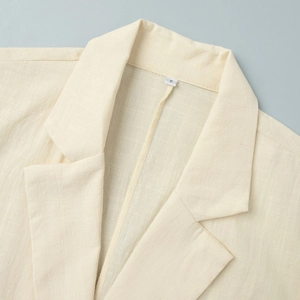 Detail shot of the cream sleeveless shirt dress collar with size S label on linen fabric