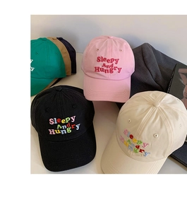 Flat lay of colorful cotton baseball caps with Sleepy And Hungry embroidery detail