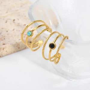 Detail of layered 18K gold stainless steel rings with turquoise and black natural stones