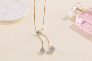 Detail of gold Y-necklace featuring three crystal-studded spherical beads on a fine chain