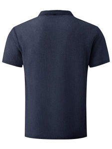 Detail of dark blue waffle knit polo shirt showing textured fabric and back tailoring