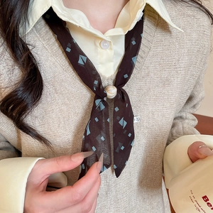 Detail of dark brown geometric print chiffon scarf with cream resin bead buckle