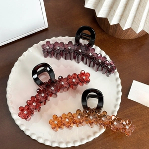 Three floral resin hair claws with rhinestones on a white plate, vintage French style