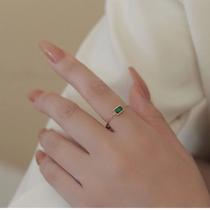Detail of adjustable gold chain ring with emerald-cut green zircon on hand
