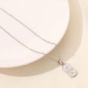 Detailed macro view of silver rectangle pendant with sun, eye, and moon engravings