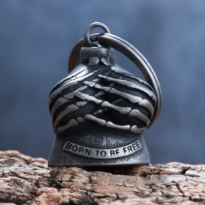 Macro detail of gothic skull bell pendant featuring 'BORN TO BE FREE' engraving on wood