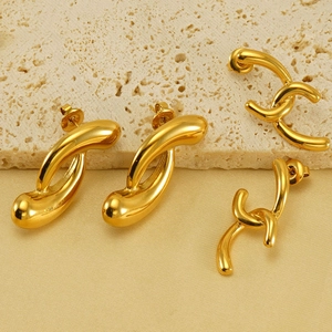 Macro detail of 18k gold plated irregular hoop and interlocking C-shaped stud earrings
