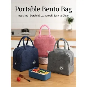Three portable insulated lunch bags in blue, pink, and grey on a wooden kitchen counter
