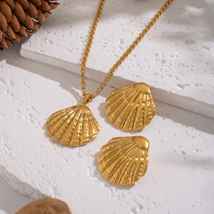 Set di gioielli a conchiglia dorata con collana e orecchini su pietra bianca