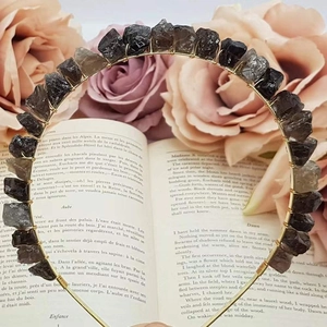 Close-up of handmade raw crystal crown with dark stones woven on vintage book background