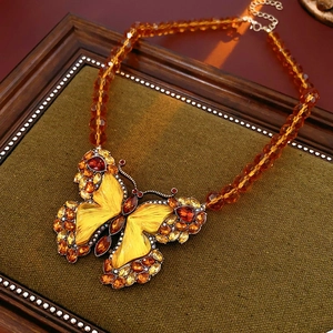 Detailed macro shot of vintage gold butterfly pendant with yellow crystals on velvet