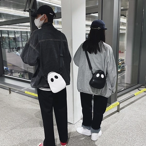 Street style shot of black and white cartoon ghost crossbody bags with adjustable straps