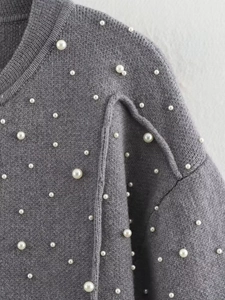 Detail of grey knitted bomber jacket featuring elegant white faux pearl embellishments