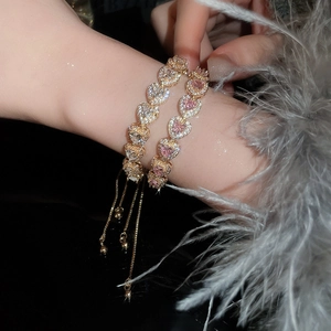 Close-up of pink and white heart crystal bracelets with adjustable gold chain on wrist