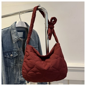 Detailed close-up of red quilted heart pattern shoulder bag with a stylish knotted strap