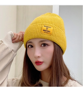 Detailed view of yellow ribbed knit beanie featuring a stitched rectangle fabric label