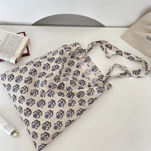 Detail of vintage floral print beige canvas tote bag with woven brand label on white table